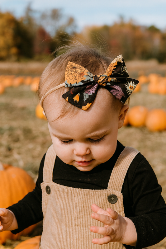 baby wearing a Halloween-themed headband with pumpkins in a pumpkin patch