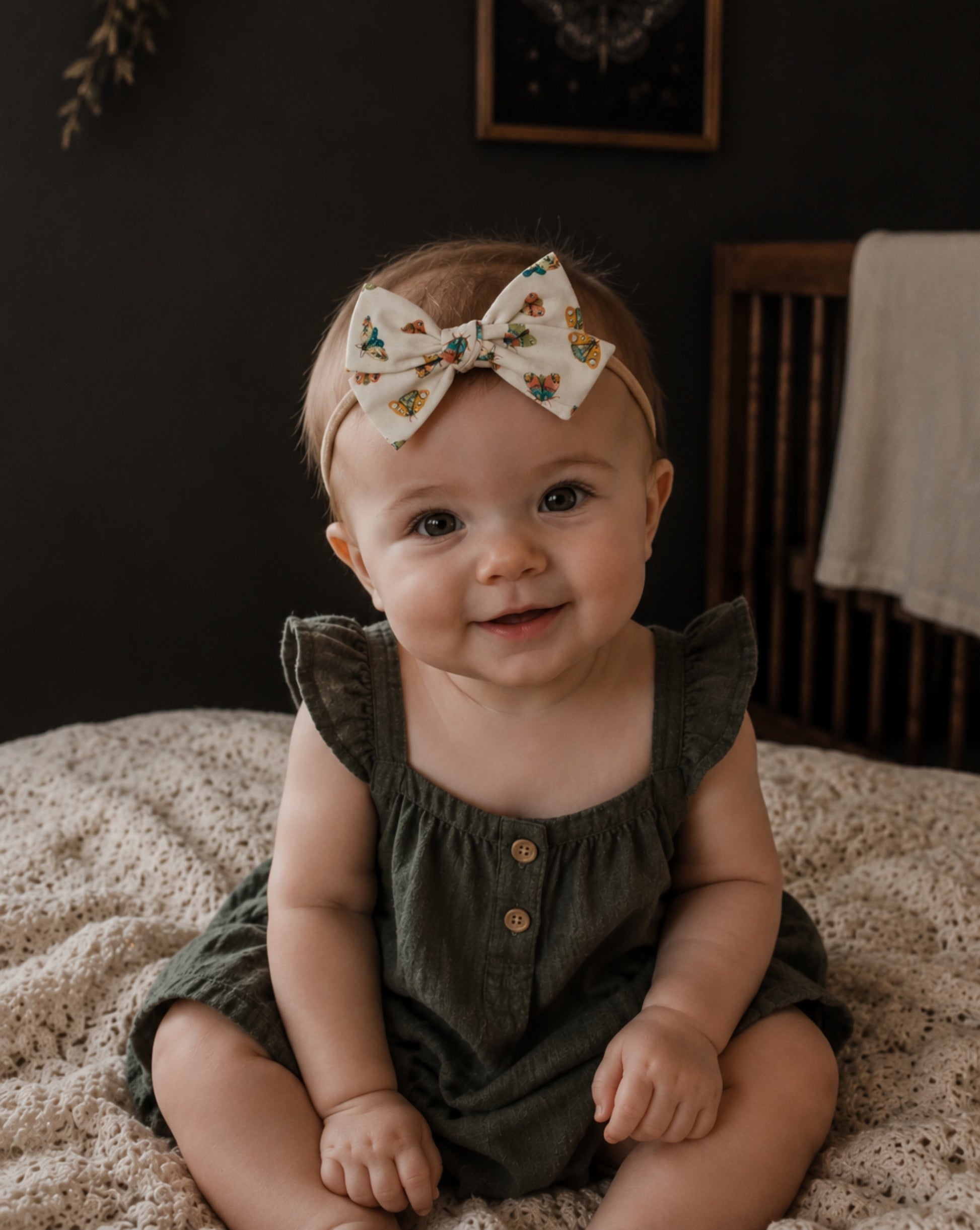 baby girl in a vintage nursery wearing a moth patterned baby bow headband